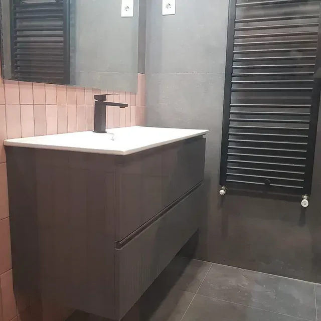 Un baño con lavabo, espejo y toallero.