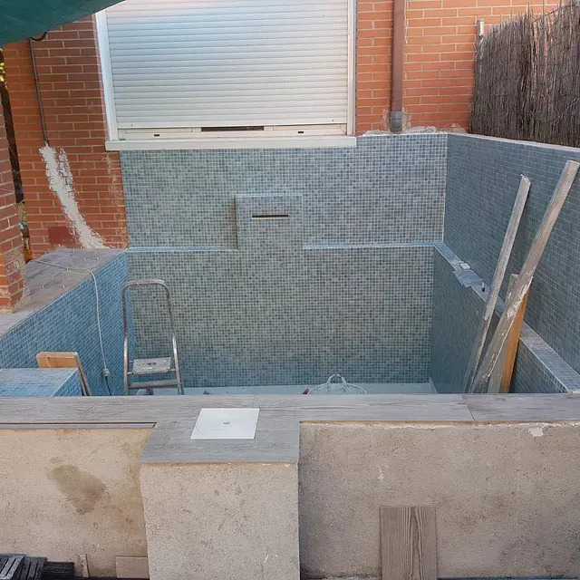 Un edificio de ladrillo con una piscina enfrente.