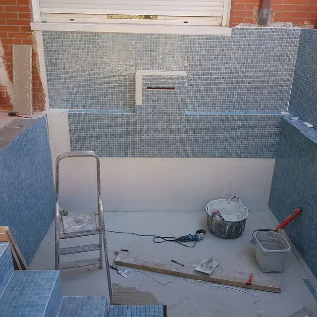 Una escalera está en el suelo al lado de un cubo de cemento.