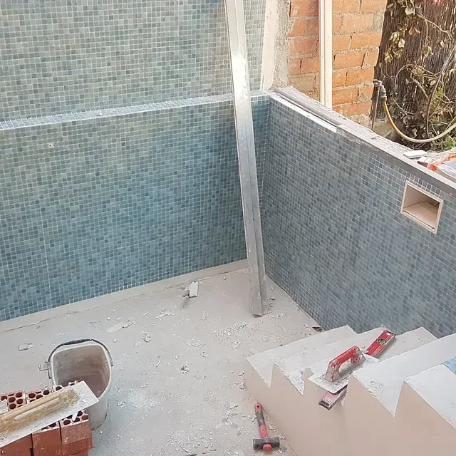 Un cubo de ladrillos está en el suelo al lado de una escalera.