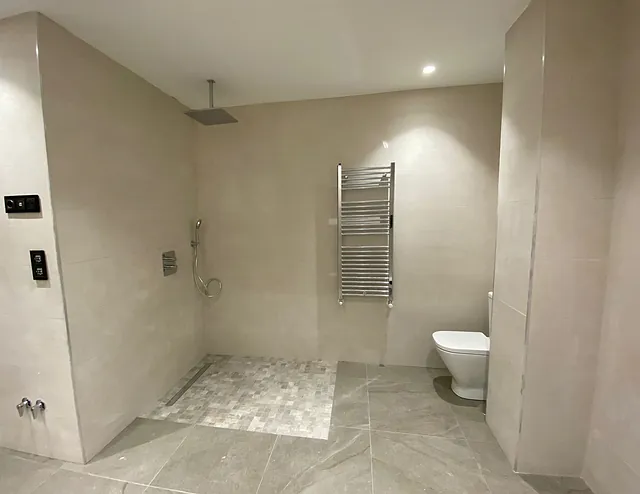 Un baño con ducha, inodoro y toallero.