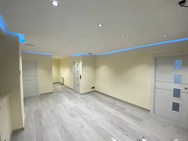 Una gran habitación vacía con suelo de madera y paredes blancas.
