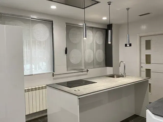 Una cocina con una isla grande, fregadero y estufa.