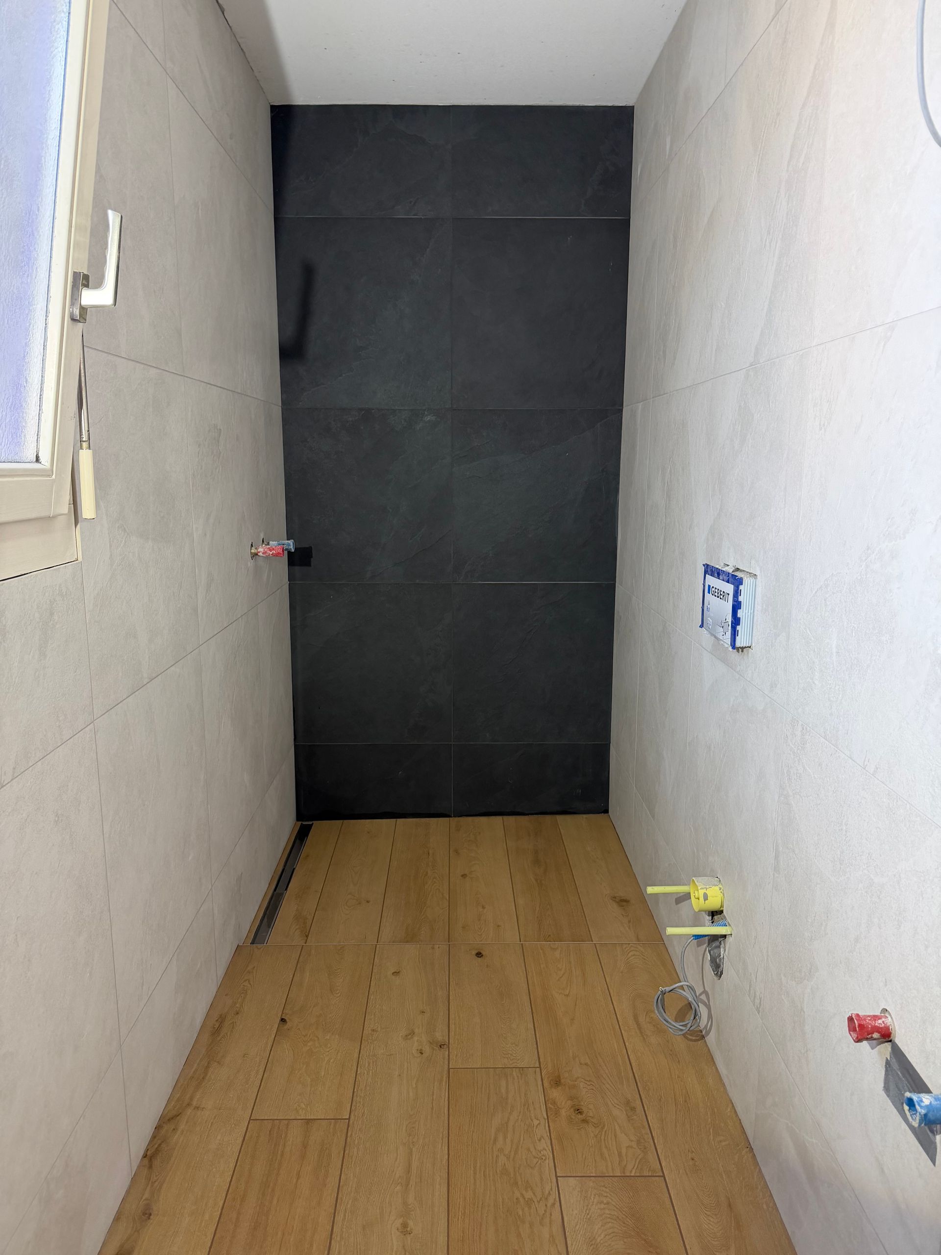 Bâtiment beige avec fenêtres à encadrement noir ; enseigne à la fenêtre du haut.