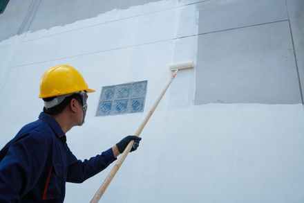 Un homme peint un mur avec un rouleau.