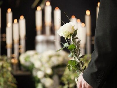 Um homem segura uma rosa branca num funeral.