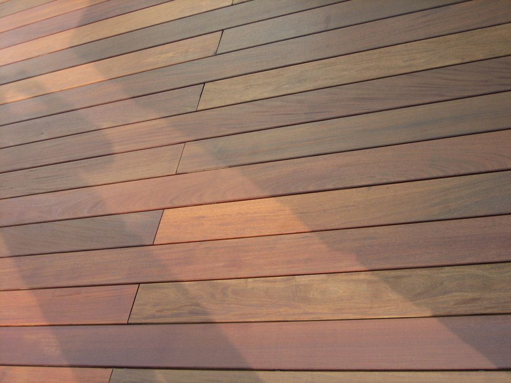 Schräg angeordnete Holzdielen der Terrasse werfen Schatten aus dem Sonnenlicht.