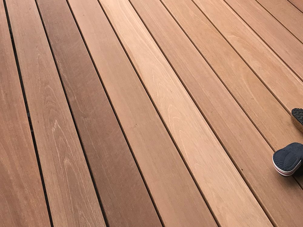 Holzdielen, einige heller, einige dunkler, rechts ist ein Fuß in einem Schuh zu sehen.