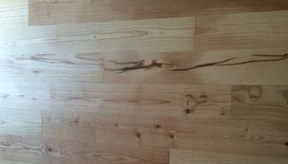 Eine Nahaufnahme eines Holzbodens mit einem Ast darin.