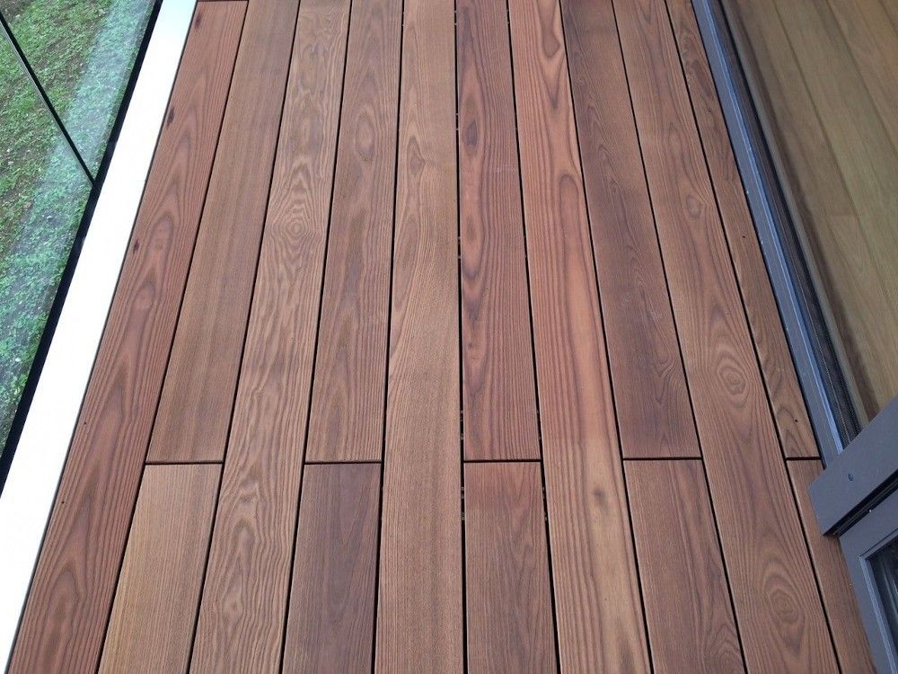 Holzterrasse mit vertikalen Dielen in verschiedenen Brauntönen.