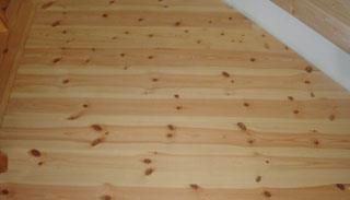 Eine Nahaufnahme eines Holzbodens mit einer Treppe im Hintergrund.