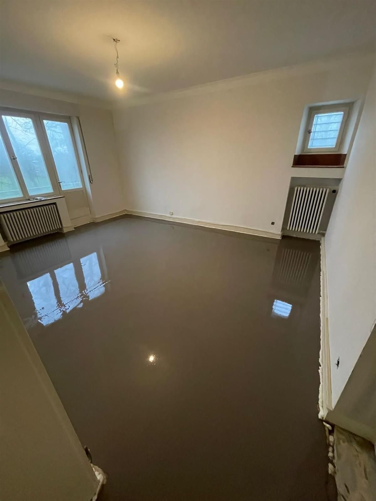 Ein Wohnzimmer mit Betonboden und weißen Wänden.