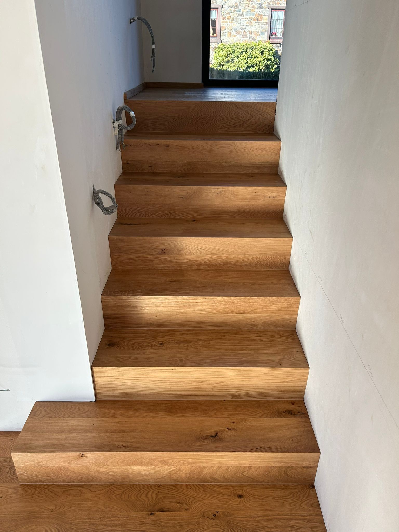 Ein hölzernes Schuhregal unter einer Treppe.