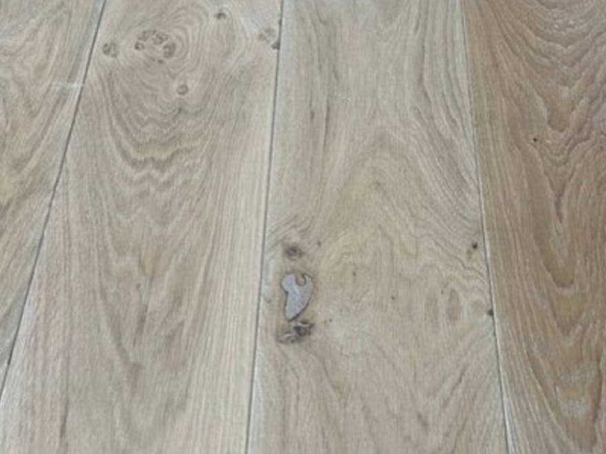 Helle Holzdielen mit einem kleinen dunklen Ast und einer Markierung in der Nähe der Mitte.