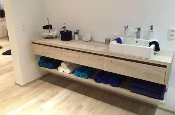 Ein Badezimmer mit Waschbecken und einem Regal voller Handtücher