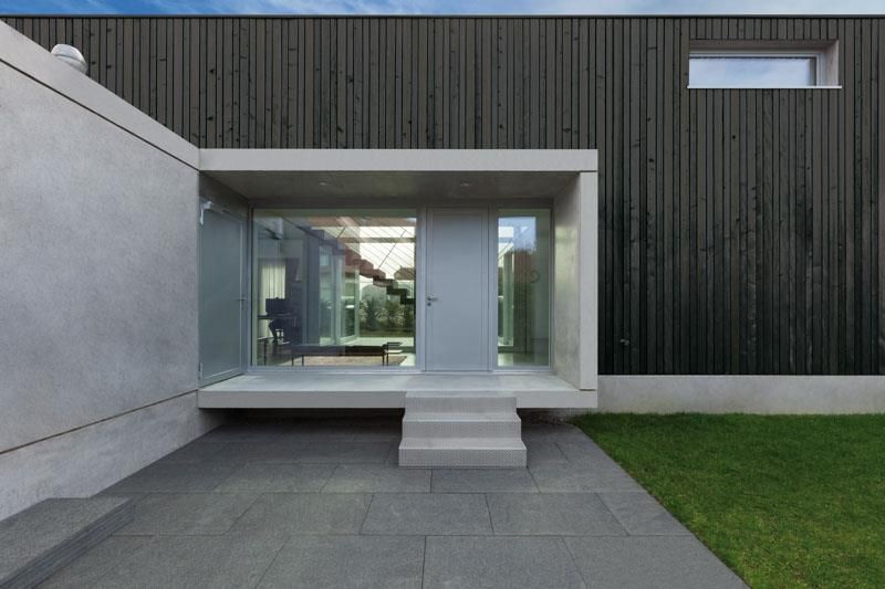 Ein modernes Haus mit einer großen Glastür und einer Treppe, die dorthin führt.