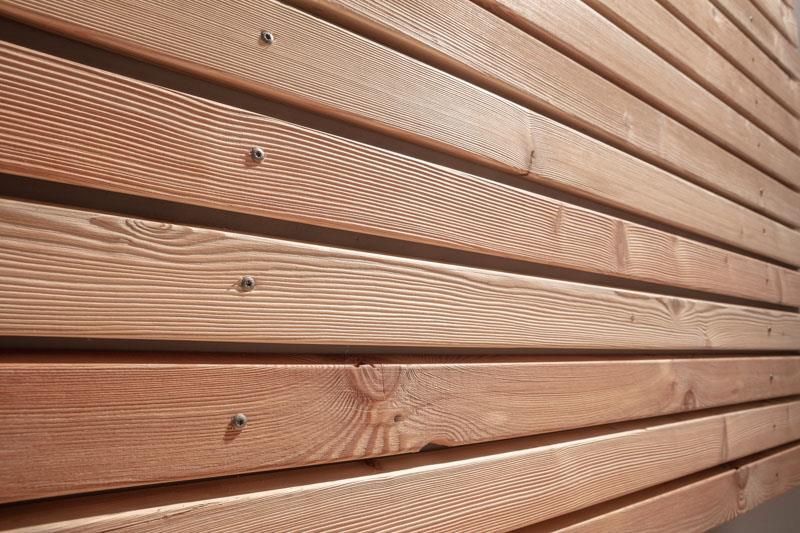 Eine Nahaufnahme einer Holzwand mit Schrauben darin.