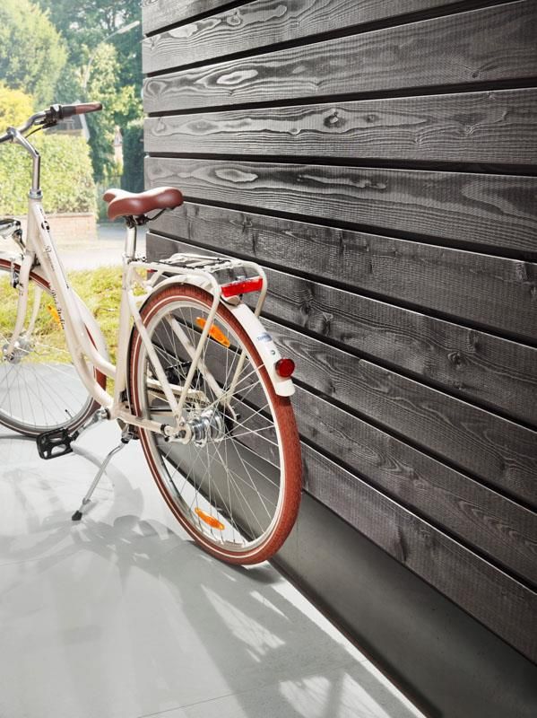 Ein Fahrrad lehnt an einer Holzwand.