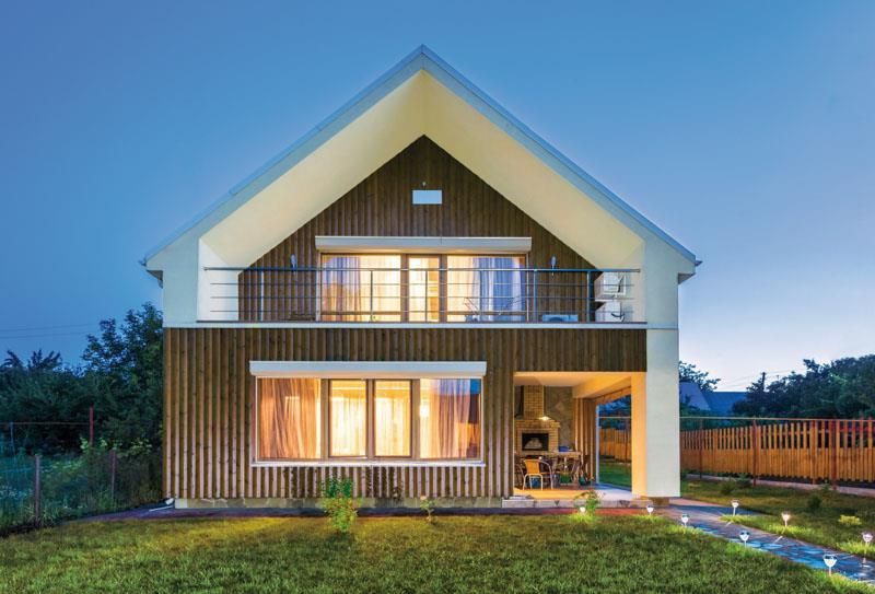 Ein Haus mit vielen Fenstern und einem Balkon ist nachts beleuchtet.