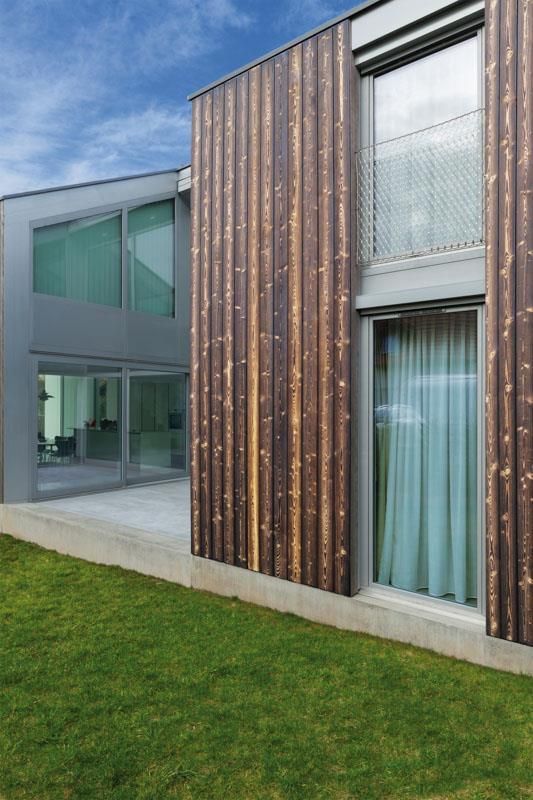Ein Haus mit vielen Fenstern und einer Wiese davor