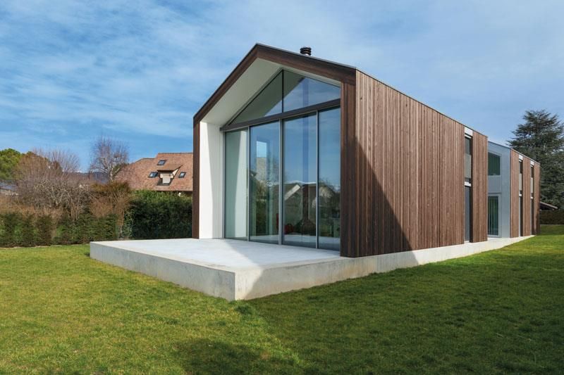 Ein kleines Haus mit vielen Fenstern steht auf einer üppigen grünen Wiese.