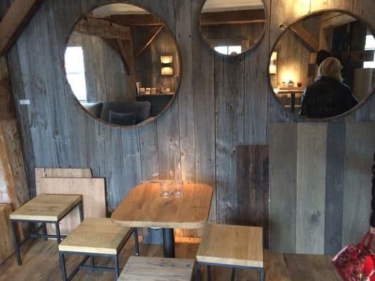 Ein Raum mit einem Tisch und Stühlen und drei Spiegeln an der Wand