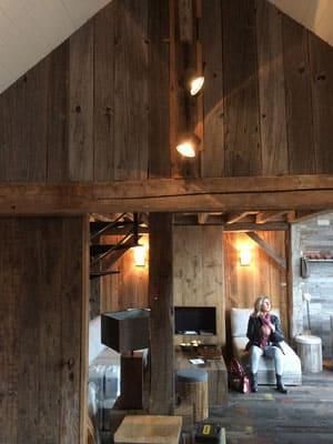 Eine Frau sitzt auf einem Stuhl in einem Wohnzimmer mit Holzwänden.