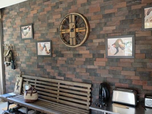 Eine Holzbank steht vor einer Backsteinmauer.