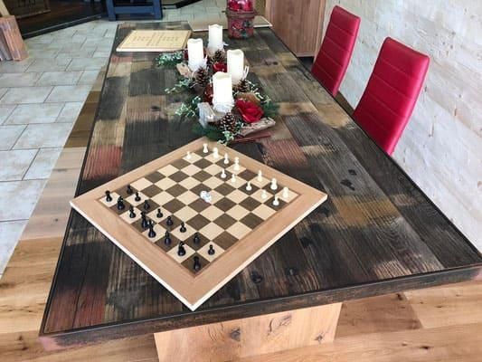 Ein Holztisch mit einem Schachbrett und Kerzen darauf