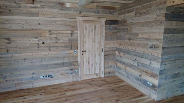 Ein Raum mit Wänden und Böden aus Holz und einer Holztür.