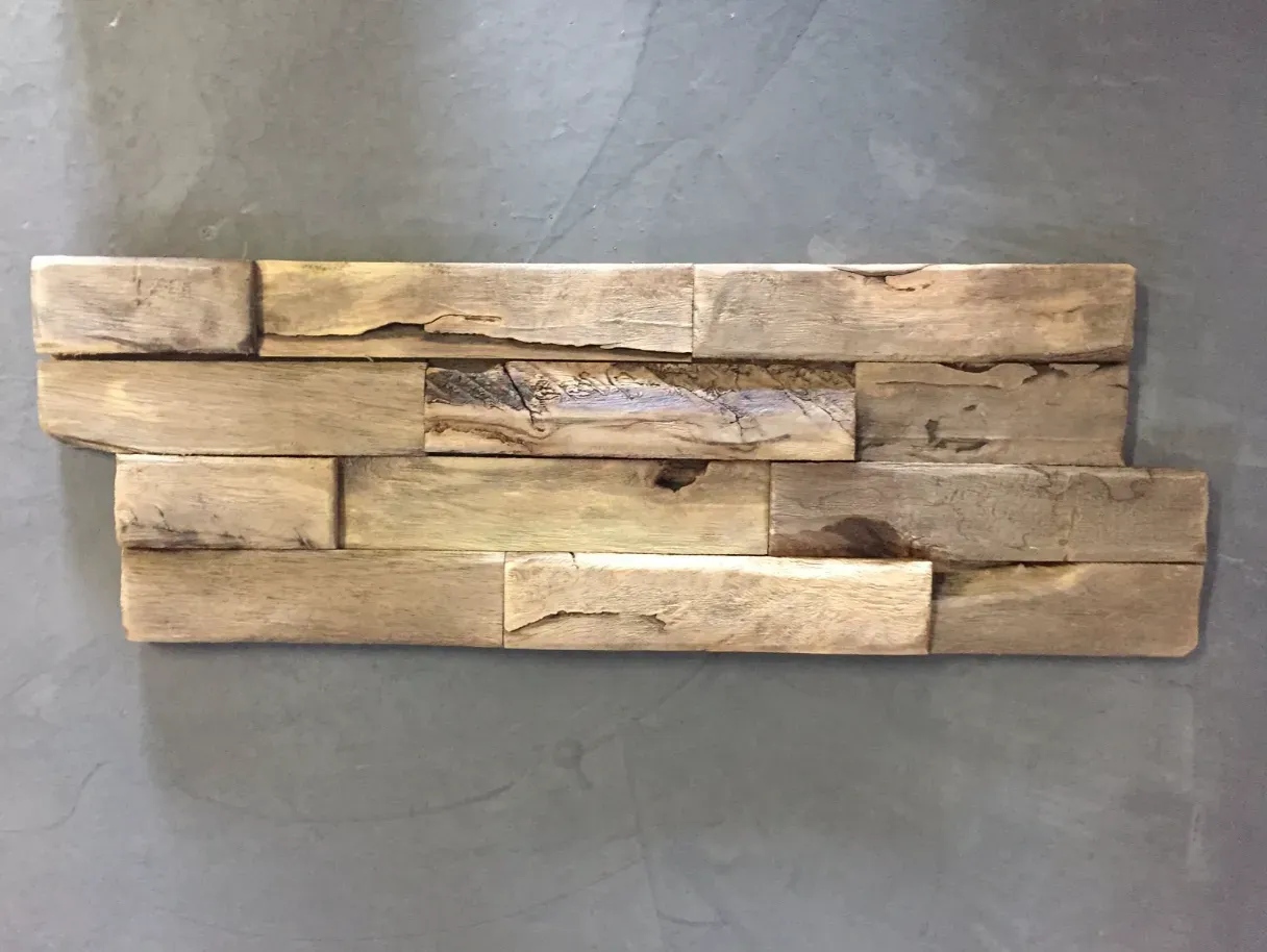 Installation von Holzwandfliesen, verschiedene Brauntöne auf grauem Hintergrund.