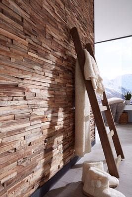 An einer Holzwand hängt eine Holzleiter.