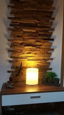 Eine Lampe steht auf einem Tisch vor einer Holzwand.