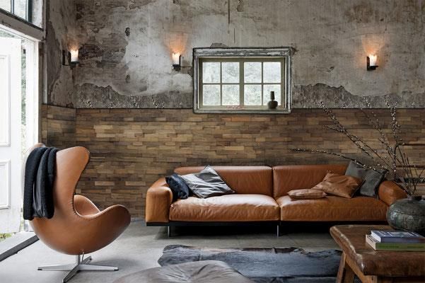 Ein Wohnzimmer mit Couch, Sessel, Tisch und Fenster.