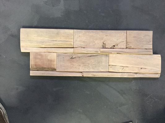 Ein Stück Holz liegt auf einer schwarzen Oberfläche.