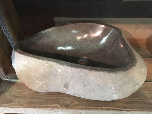 Auf einem Holztisch steht ein großes Waschbecken aus Stein.
