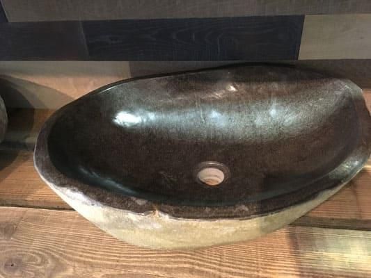 Auf einem Holztisch steht ein schwarzes Waschbecken.