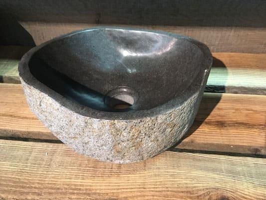 Auf einem Holztisch steht ein Steinwaschbecken.