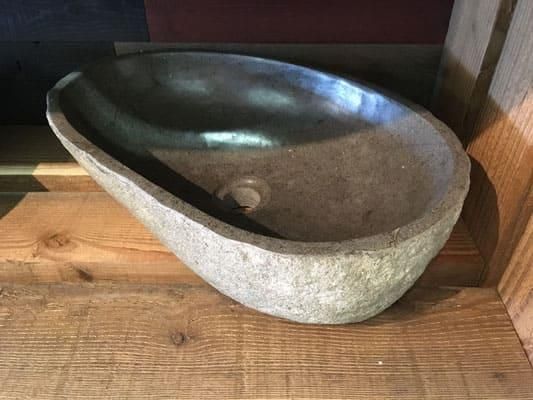Auf einem Holztisch steht ein Steinwaschbecken.