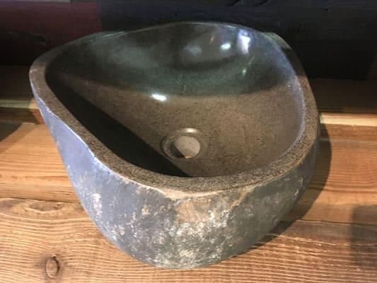 Auf einem Holztisch steht ein Steinwaschbecken.