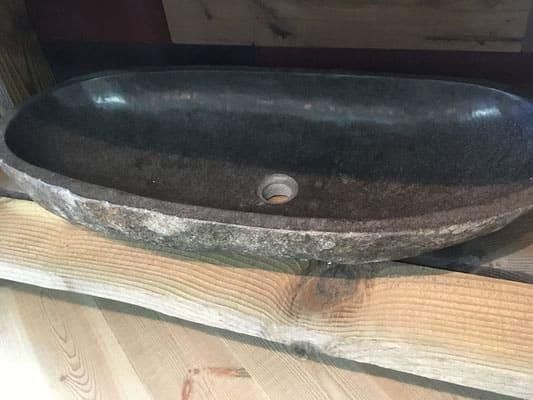 Auf einem Holztisch steht ein Steinwaschbecken.