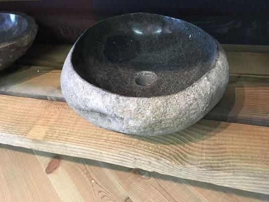 Auf einem Holztisch steht ein Steinwaschbecken.