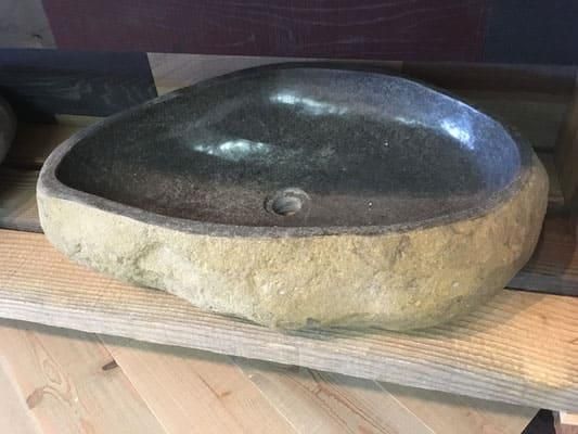 Auf einem Holztisch steht ein Steinwaschbecken.