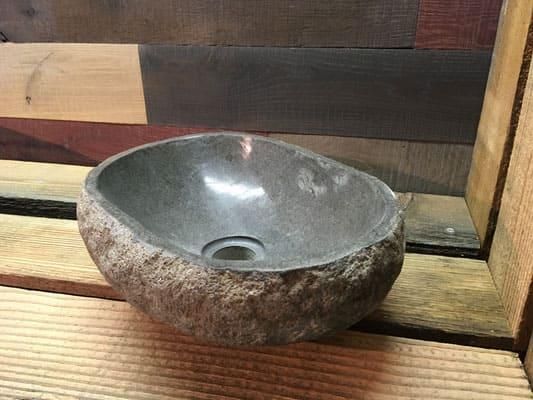 Auf einem Holztisch steht ein kleines Steinwaschbecken.