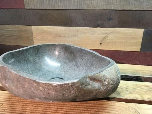 Auf einem Holztisch steht ein Steinwaschbecken.