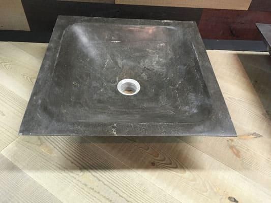 Auf einem Holztisch steht ein quadratisches Waschbecken.