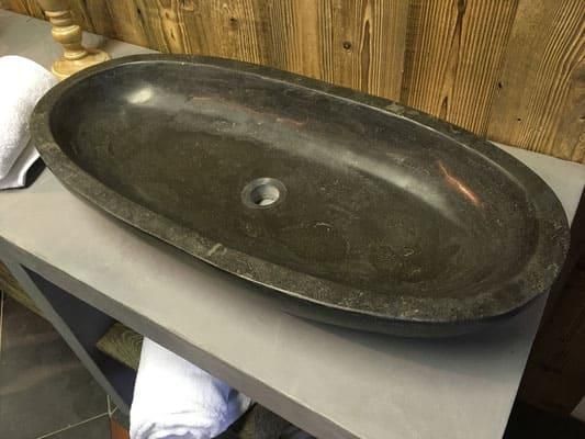 Ein schwarzes Waschbecken steht auf einer Ablage in einem Badezimmer.