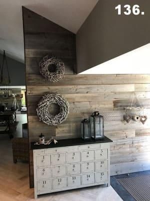 Eine weiße Kommode steht vor einer Holzwand.