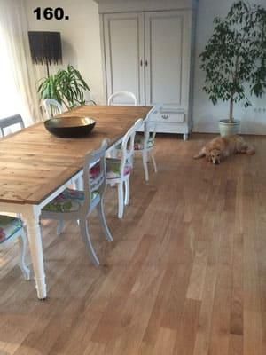 Ein Esszimmer mit einem Holztisch und Stühlen und einem Hund, der auf dem Boden liegt.
