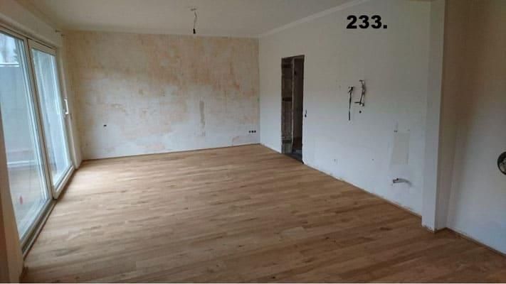 Ein großer leerer Raum mit Holzboden und Glasschiebetüren.